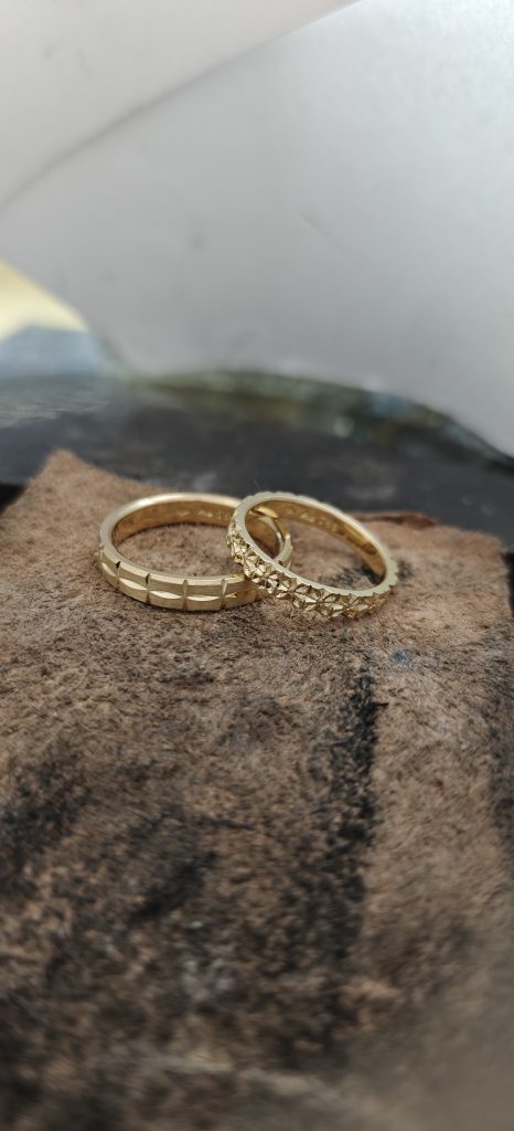 Zwei handgefertigte Goldringe mit geometrischem Muster auf Naturleder, Schmuckdesign vom Goldschmied
